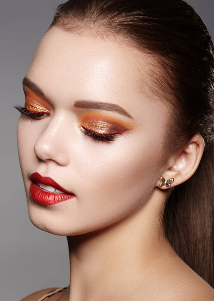 Closeup portrait of Woman Face with Gold glitter Make-up, bright red liner on Eyes. Fashion Celebrate Makeup, Glowy Skin. Shiny Simmer and metalic eye shadows - Photo, image