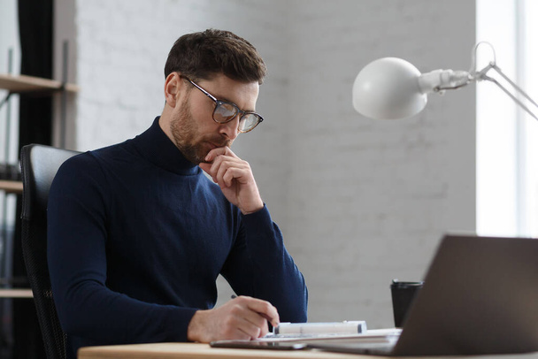 Architect working in office with blueprints.Engineer inspect architectural plan, sketching a construction project.Portrait of handsome bearded man sitting at workplace. Business construction concept - Foto, imagen