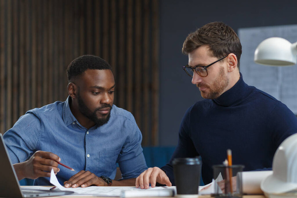 Multiracial engineer team working in office with blue prints and architect equipment sketching,discussing and planning construction project. Partners disputing at work. Business construction concept - Фото, зображення