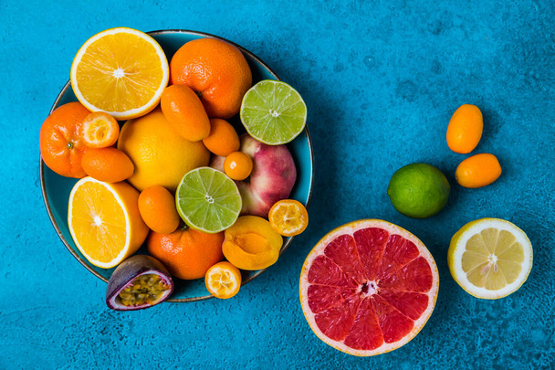 Lato i owoce cytrusowe w misce na niebieskim tle. Koncepcja zdrowego odżywiania. - Zdjęcie, obraz