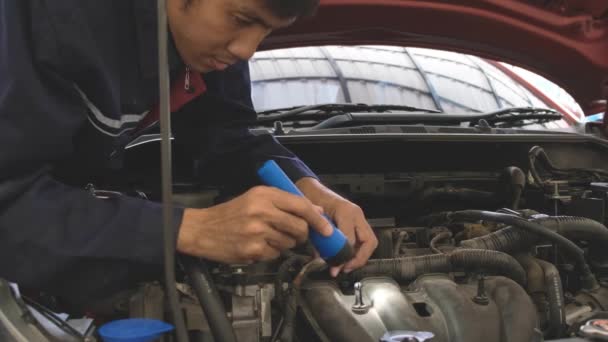 Asyalı bir adamın el feneriyle arabanın motorunu kontrol ederken görüntüsü. Araba tamir istasyonu ya da teknisyen uzmanı konsepti - Video, Çekim