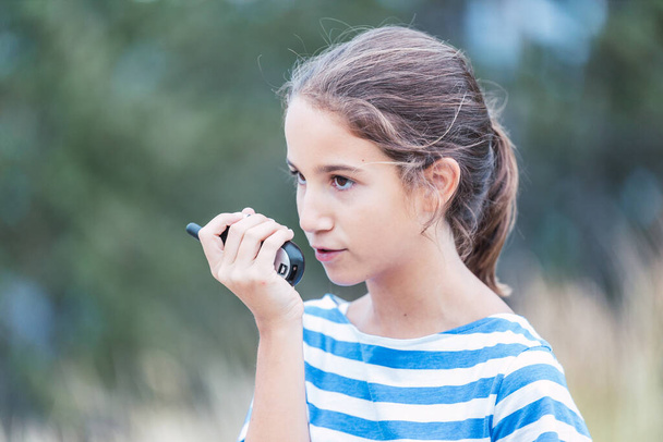 close-up van een mooi meisje praten met een walkie-talkie buiten - Foto, afbeelding
