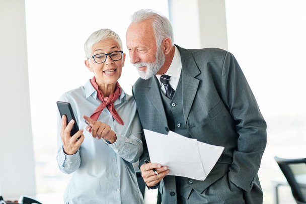 portret dwóch starszych biznesmenów rozmawiających przez telefon komórkowy w biurze  - Zdjęcie, obraz