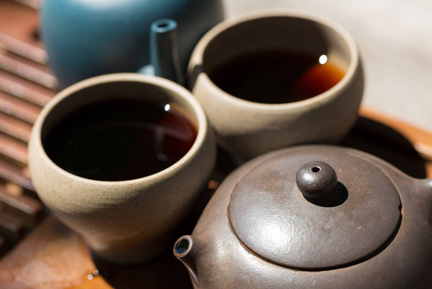 Chinese tea ceremony. Ceramic teapot made of clay and bowls on a wooden background. - 写真・画像