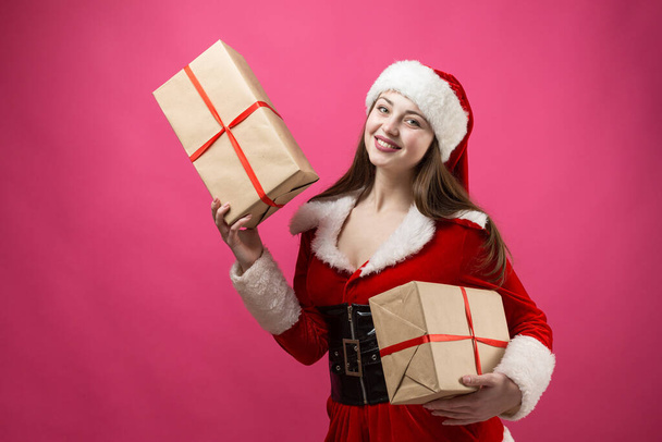 Mooie jonge vrouw in Santa Claus kostuum tegen de rode achtergrond. - Foto, afbeelding