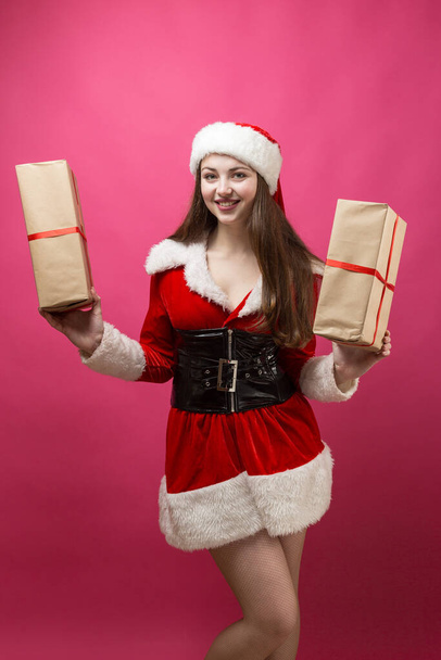 Krásná mladá žena v kostýmu Santa Claus proti červenému pozadí. - Fotografie, Obrázek