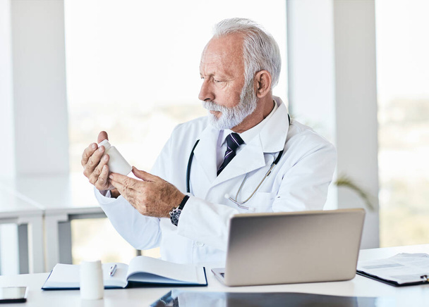 portrait of a senior doctor holding abottle of medication  in a hospital  - Фото, зображення