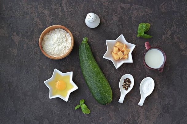 Ingredients for cooking zucchini wafers on a dark concrete background. Top view, copy space. Italian food. Healthy food. - Photo, image