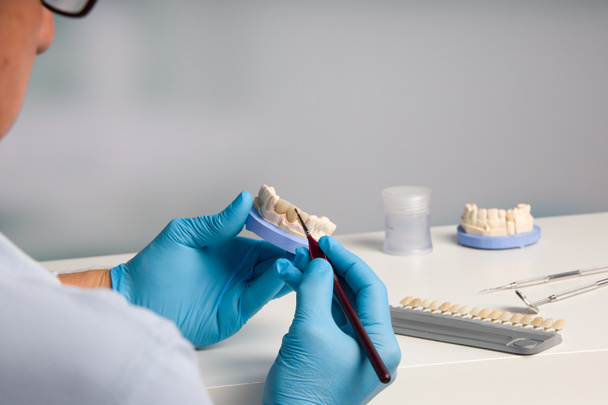 primer plano del técnico dental pintando corona dental en laboratorio dental - Foto, imagen