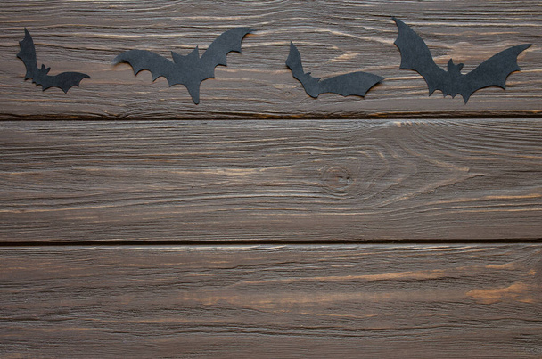 Happy Halloween holiday background with craft paper in the form of bats on wooden table. Halloween holiday celebration with decoration. - Photo, Image
