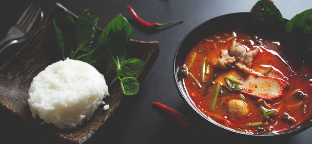 Panoraama banneri web, Thai ruoka tausta käsite. Thaimaan keittiön ruokalaji. Tom yum sianliha keitto musta ruokalaji, riisi puinen levy pöydällä tumma tausta 2 - Valokuva, kuva