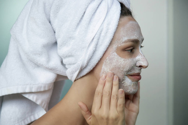 Junge Frau im Badezimmer, eingewickelt in Handtücher mit Gesichtsmaske. Home SPA und Hautpflegekonzept. - Foto, Bild