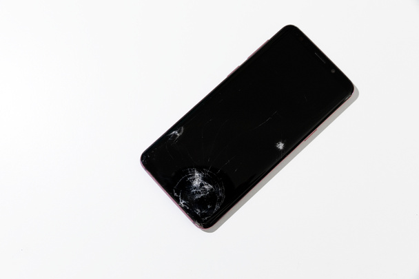 Rozbity telefon, rozbity ekran przedniego szkła w rogu smartfona widok z góry  - Zdjęcie, obraz