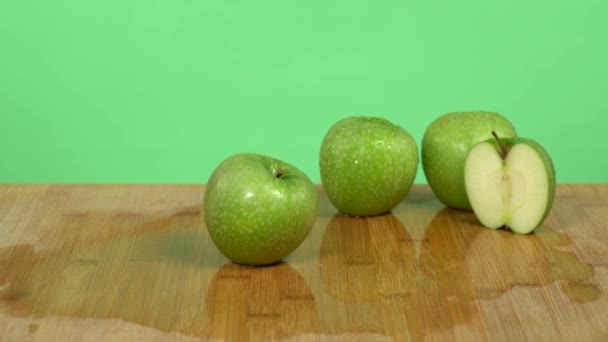 Le mani caucasiche mostrano un coltello e fanno il taglio falso di una mela verde in metà. Studio sfondo verde - Filmati, video