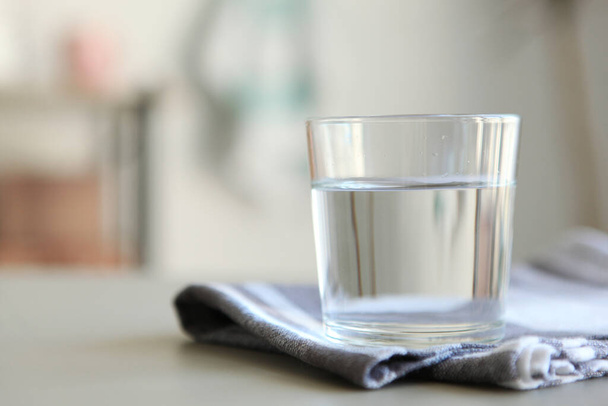 Διαυγές νερό σε ένα ποτήρι και μπουκάλι στο τραπέζι - Φωτογραφία, εικόνα