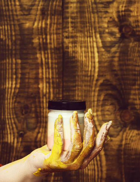 female hand holding jar on brown vintage studio background, copy space - Foto, imagen