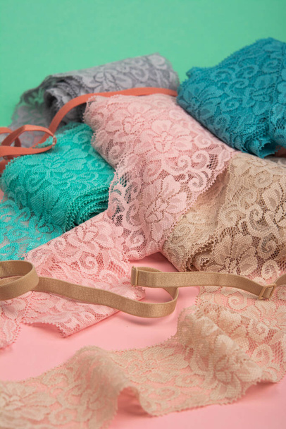 Abstract background with pile of color lace for Lingerie, panties, and bras on pink background. Delicate sophisticated glamorous elastic material. Using for Atelier and fabric store. - Photo, Image