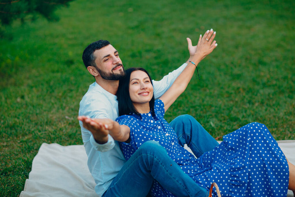 Mladý dospělý žena a muž pár piknik na zelené trávě louka v parku s otevřenou náručí - Fotografie, Obrázek