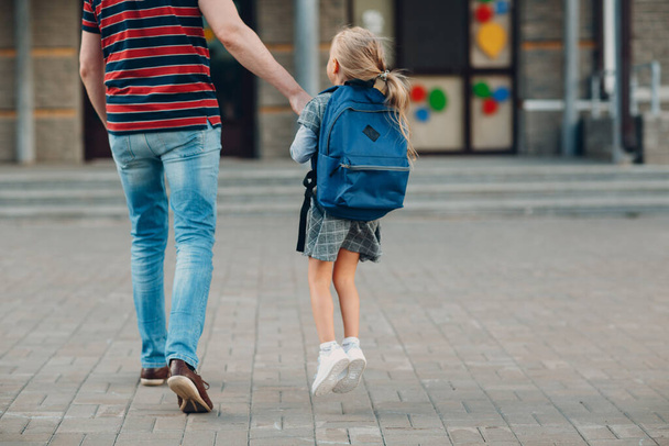 Widok ojca wracającego do szkoły z córką niosącą plecak. - Zdjęcie, obraz