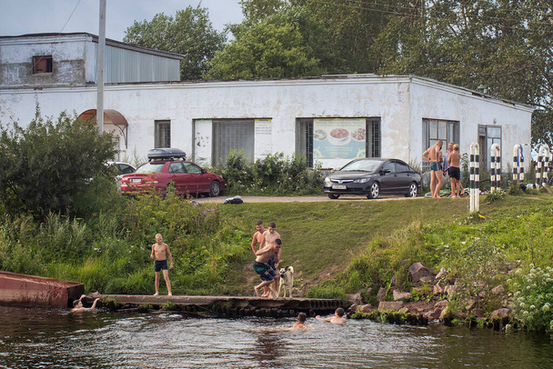 BELOZERSK, RUSSIA - 03 August 2020, Embankment in the city of Belozersk. Vologda Region. Boys swim in a canal near the lake - Foto, Imagen