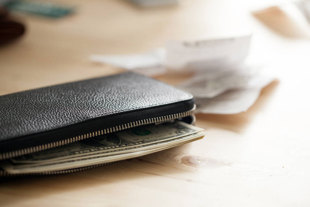 Lederen portemonnee met cash op de houten tafel met wat cheques - Foto, afbeelding