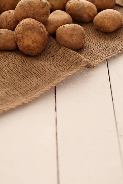 Rustieke verse ongepelde aardappelen op een houten tafel  - Foto, afbeelding