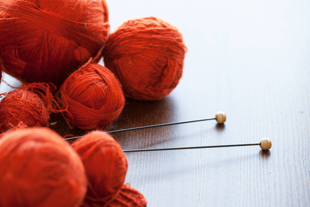 Oranje breiwerk met draadballen en naalden in een mandje - Foto, afbeelding