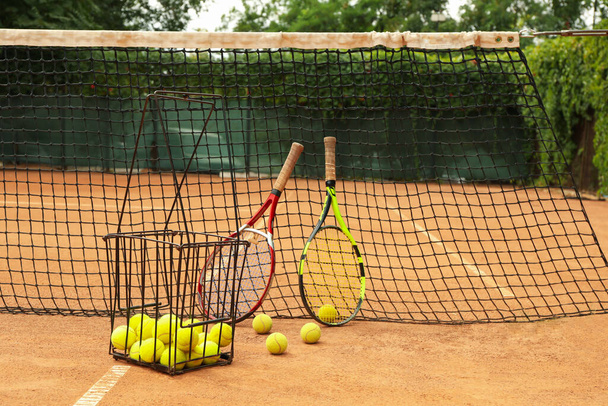Racchette e palline da tennis contro rete su campo in terra battuta - Foto, immagini