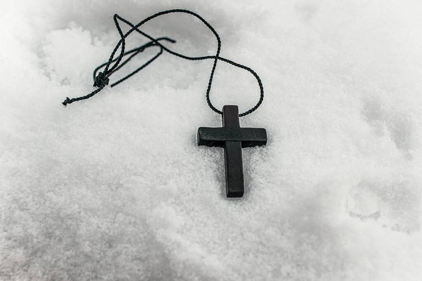 Ein Kreuz mit Faden liegt im Schnee, der den Glauben verloren hat - Foto, Bild