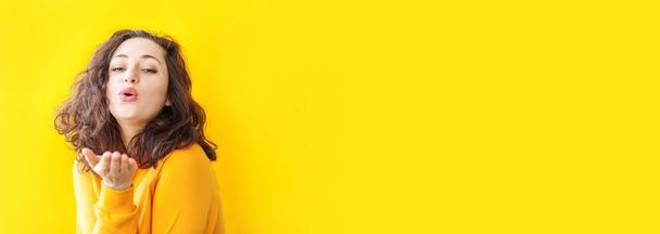 Love, peace. Beauty portrait young happy positive woman posing with kiss face expression showing love sign on yellow background isolated. European girl. Positive human emotion. Banner - Φωτογραφία, εικόνα
