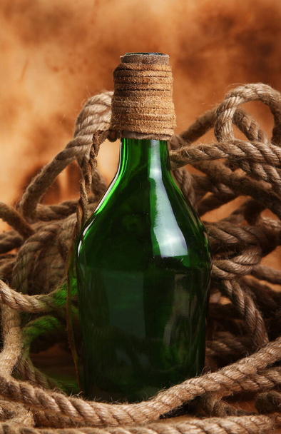 Παλιό μπουκάλι και σχοινί σε αρχαίο φόντο - Φωτογραφία, εικόνα