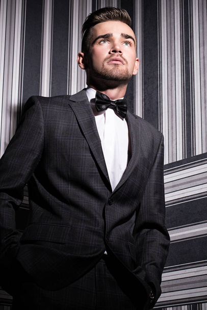 Muotokuva komea mies puku ja solmio, joka poseeraa raidallinen tausta - Valokuva, kuva