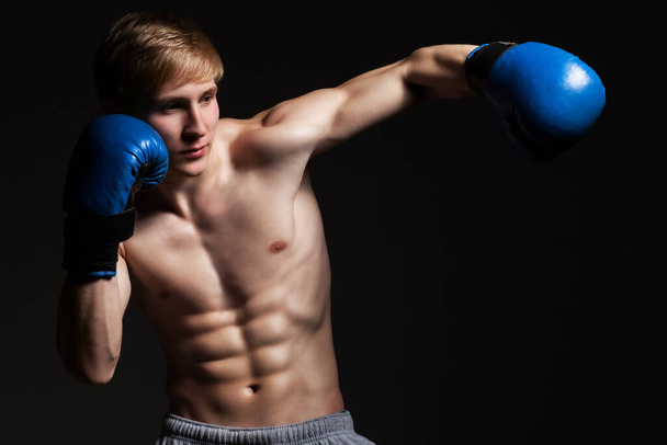 Jeune beau boxeur dans un mouvement sur fond sombre - Photo, image