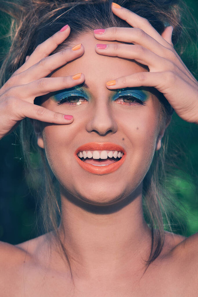 Un retrato de una chica posando con hermoso maquillaje artístico y coloridas pulseras hechas a mano - Foto, imagen