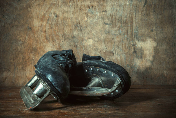 Old black leather skates on a wooden table in a retro style - 写真・画像