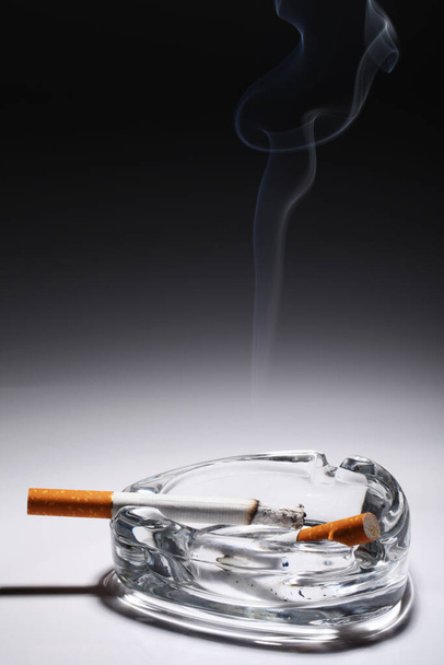 Sigaret in de asbak over grijs verloop - Foto, afbeelding