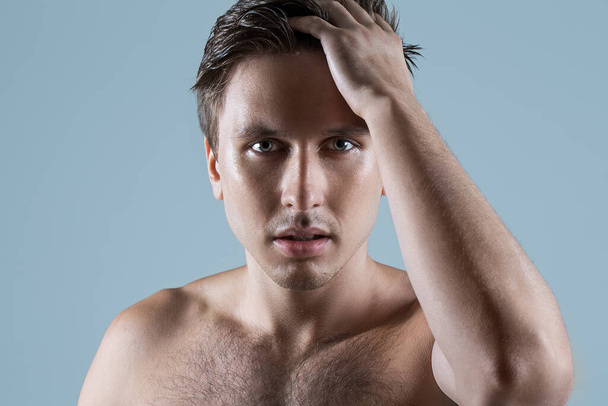 Портрет красивого чоловіка, який позує зі своїм торсом голим на світло-блакитному тлі
 - Фото, зображення