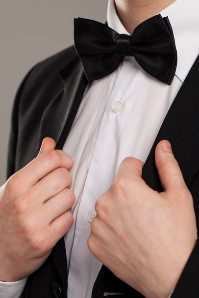 Τα αντρικά χέρια αγγίζουν το παπιγιόν σε ένα κοστούμι - Φωτογραφία, εικόνα