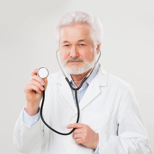 Красивый пожилой врач в форме изолирован на светлом фоне
 - Фото, изображение