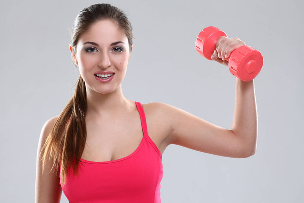 Beautiful caucasian woman in fitness wear with dumbbells over background - 写真・画像