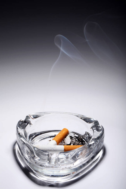 Zigarette im Aschenbecher über grauem Gefälle - Foto, Bild