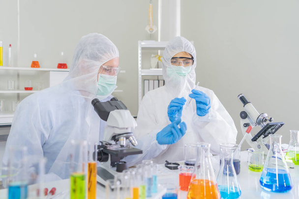 A western scientists couple working on test tube to analysis and develop vaccine of covid-19 virus in lab or laboratory in technology medical, chemistry, healthcare, research. Experimental science. - Фото, зображення
