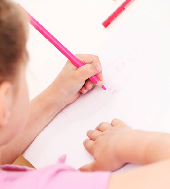 Χαριτωμένο κοριτσάκι σχέδιο στο χαρτί με πολύχρωμα μολύβια - Φωτογραφία, εικόνα