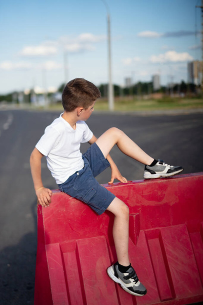 boy with white skin sitting on  road fence, concept of playing on prohibited territory - Zdjęcie, obraz