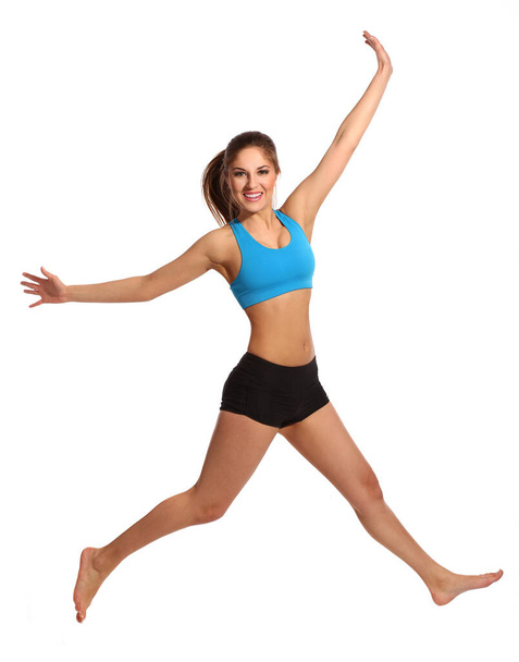 Beautiful active woman in a fitness wear jumping isolated over white background - Zdjęcie, obraz