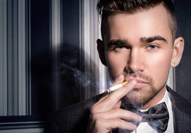 Portrait of a handsome man in a suit with a cigarette - Фото, изображение