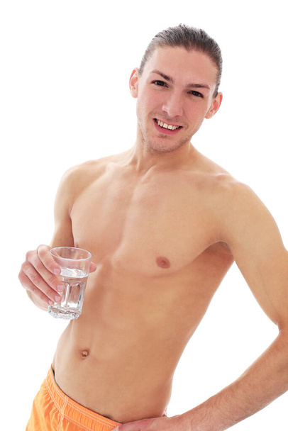 Portrait d'un bel homme torse nu qui boit de l'eau sur un fond blanc - Photo, image