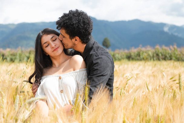 Szerető pár csók közepén egy búza mező - spanyol fiatalok élvezik a természet naplementekor - Fotó, kép
