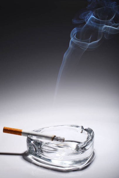Zigarette im Aschenbecher über grauem Gefälle - Foto, Bild