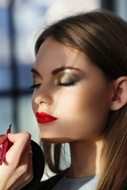 Beautiful woman with red lipstick during make-up - Fotó, kép